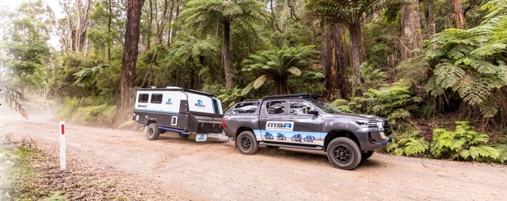 side view 4x4 ute towing a caravan in the Forrest on dirt road